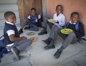Four boys in school uniform enjoying a meal