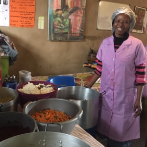 A volunteer at Yiza Ekhaya standing with big pots of food
