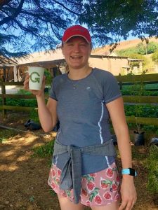 A woman in sports gear holding a Green Home cup and smiling