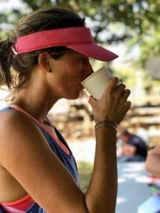 A women in sports clothes drinking out of GREEN HOME cup