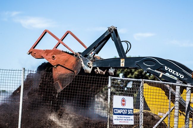 A forklift turning compost at a composting site