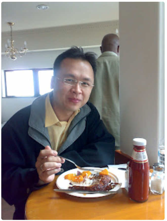 A Chinese man eating from a Green Home bagasse plate and smiling at camera